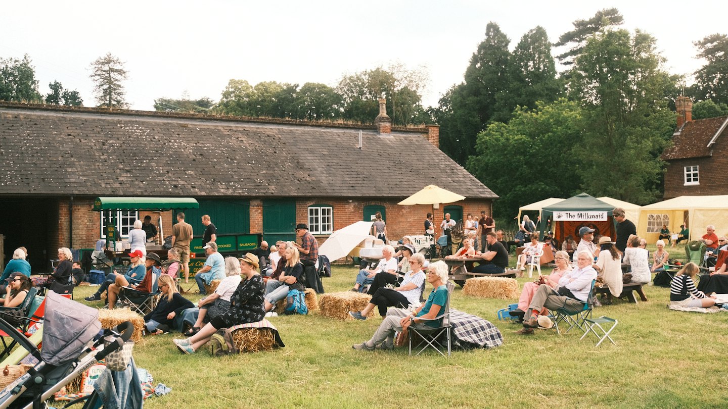 Diverse people enjoy a community event outdoors on a grassy field.